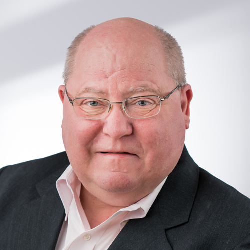 Lynn Attwood, headshot of man in suit and white shirt without tie