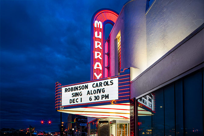 Outside Murray theater at night with glowing neon sign and marquee